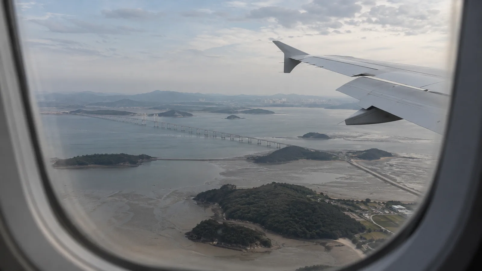 View from a plane window of a long bridge, islands and tidal flats on the approach to Incheon Airport