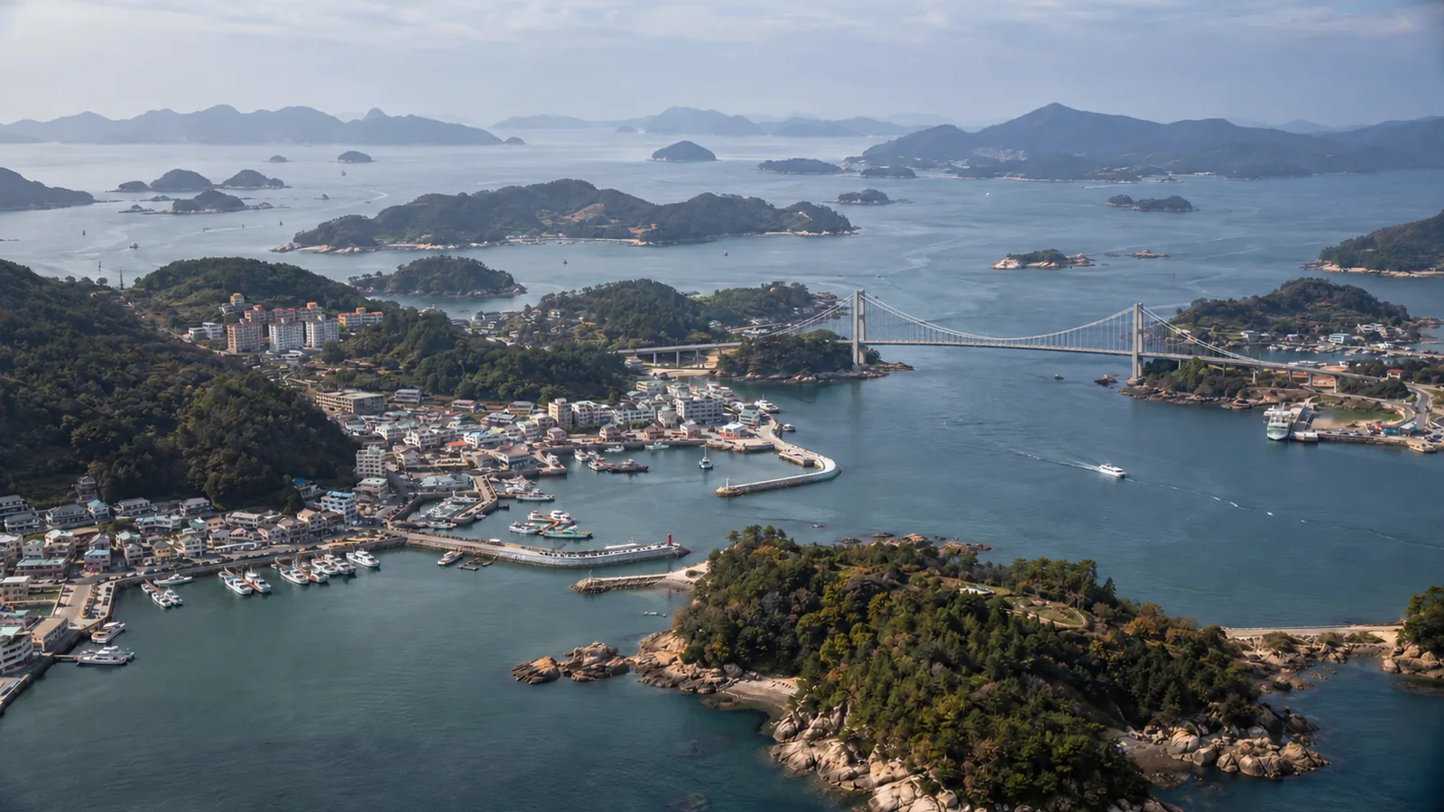 Aerial view of a harbor town, a suspension bridge and wooded islands off South Korea's southern coast